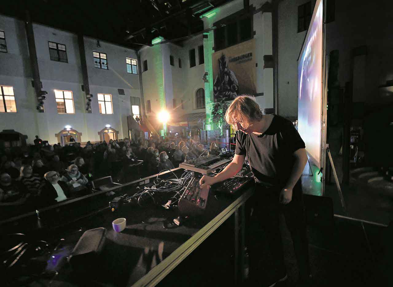 DJ Domink Eulberg steht auf einem Balkon, vor ihm das Publikum.