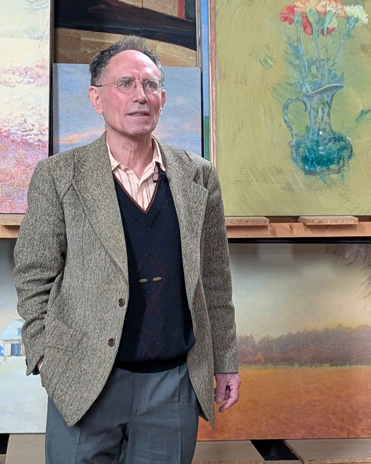 Benedikt Forster steht vor einigen seiner Gemälde.