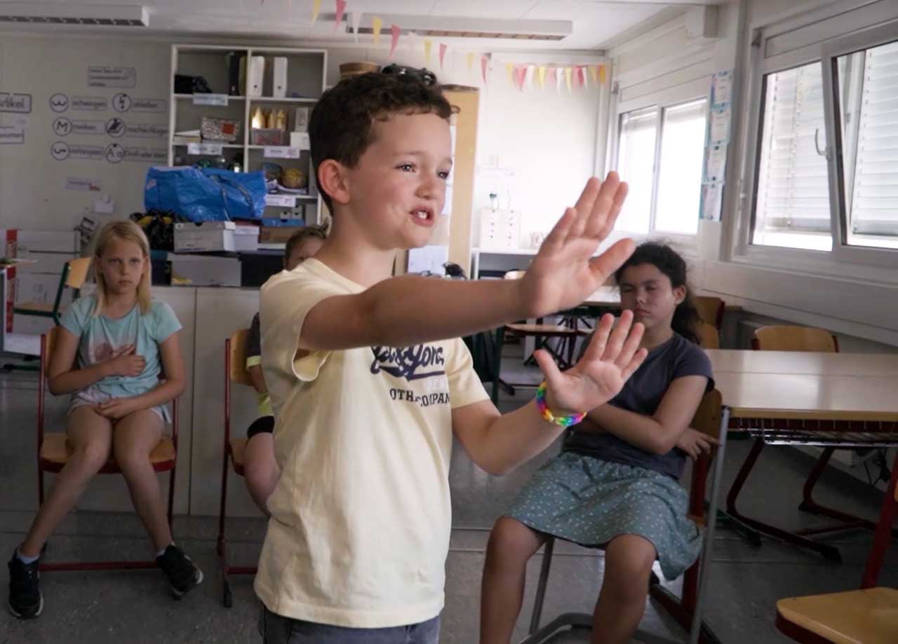 Junge mit gelben Shirt wirft seine Hände vor sich
