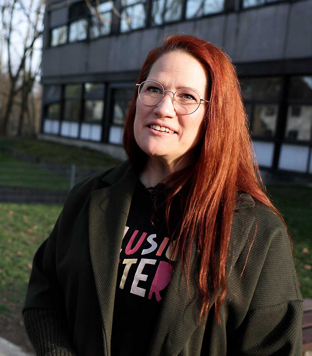 Nina steht draußen und blickt an der Kamera vorbei.