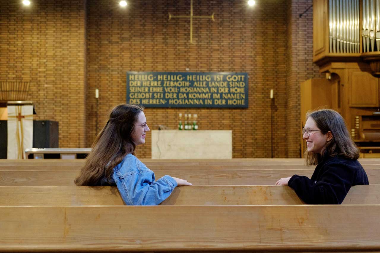 Luisa Eizenhöfer (links) und Nina Maskus sitzen in der Evangelischen Altmuenstergemeinde in Mainz in der Kirchenbank.