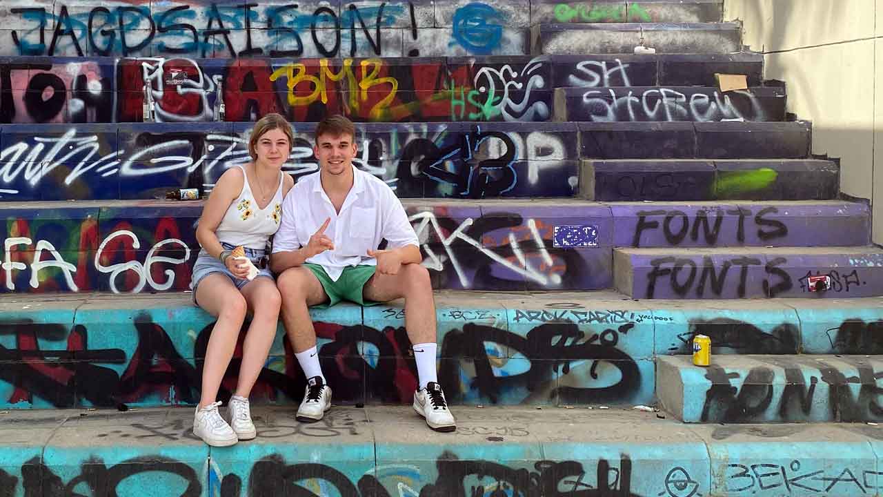 Rosalie und Simon sitzen auf den bunten Stufen in Barcelona