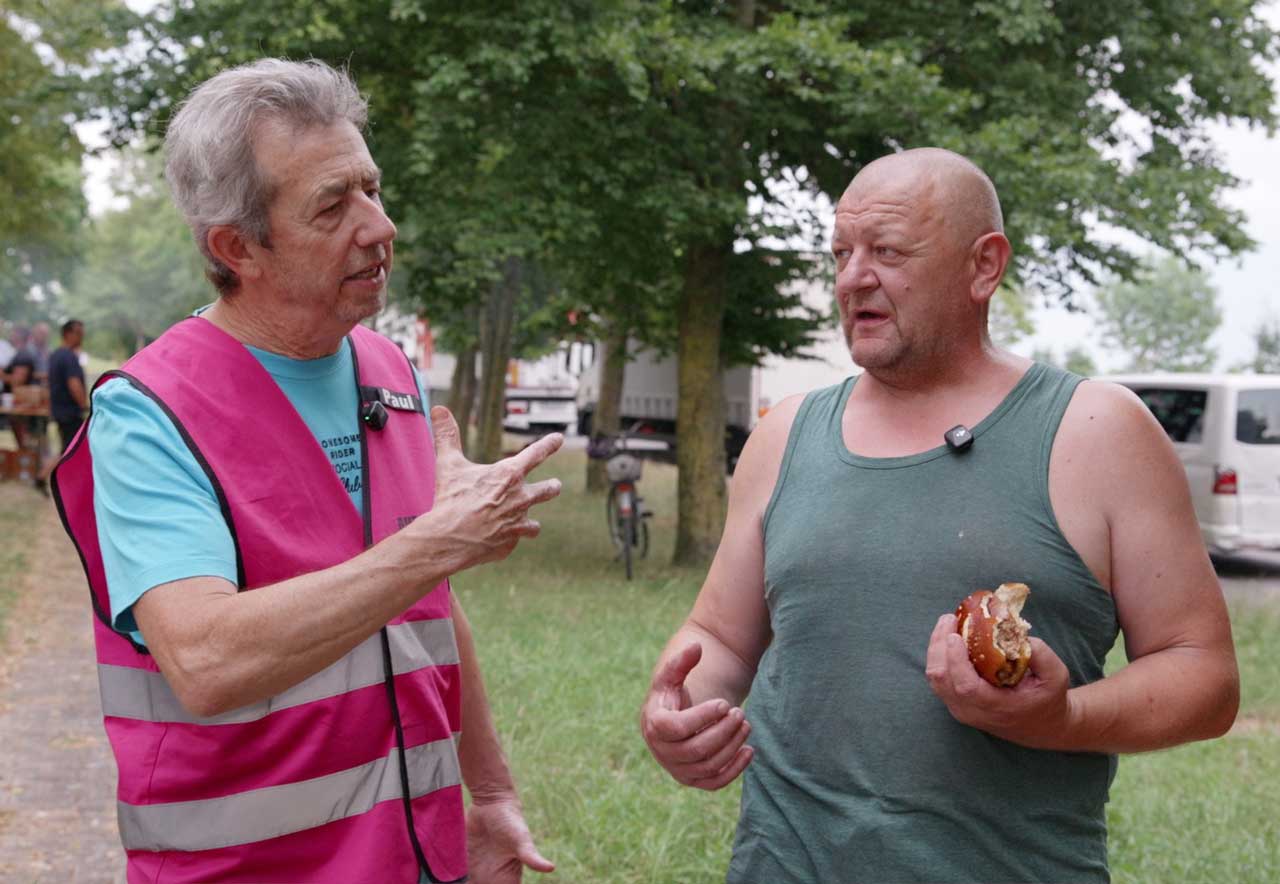 Links der Seelsorger, rechts der Trucker mit einem Brötchen in der Hand