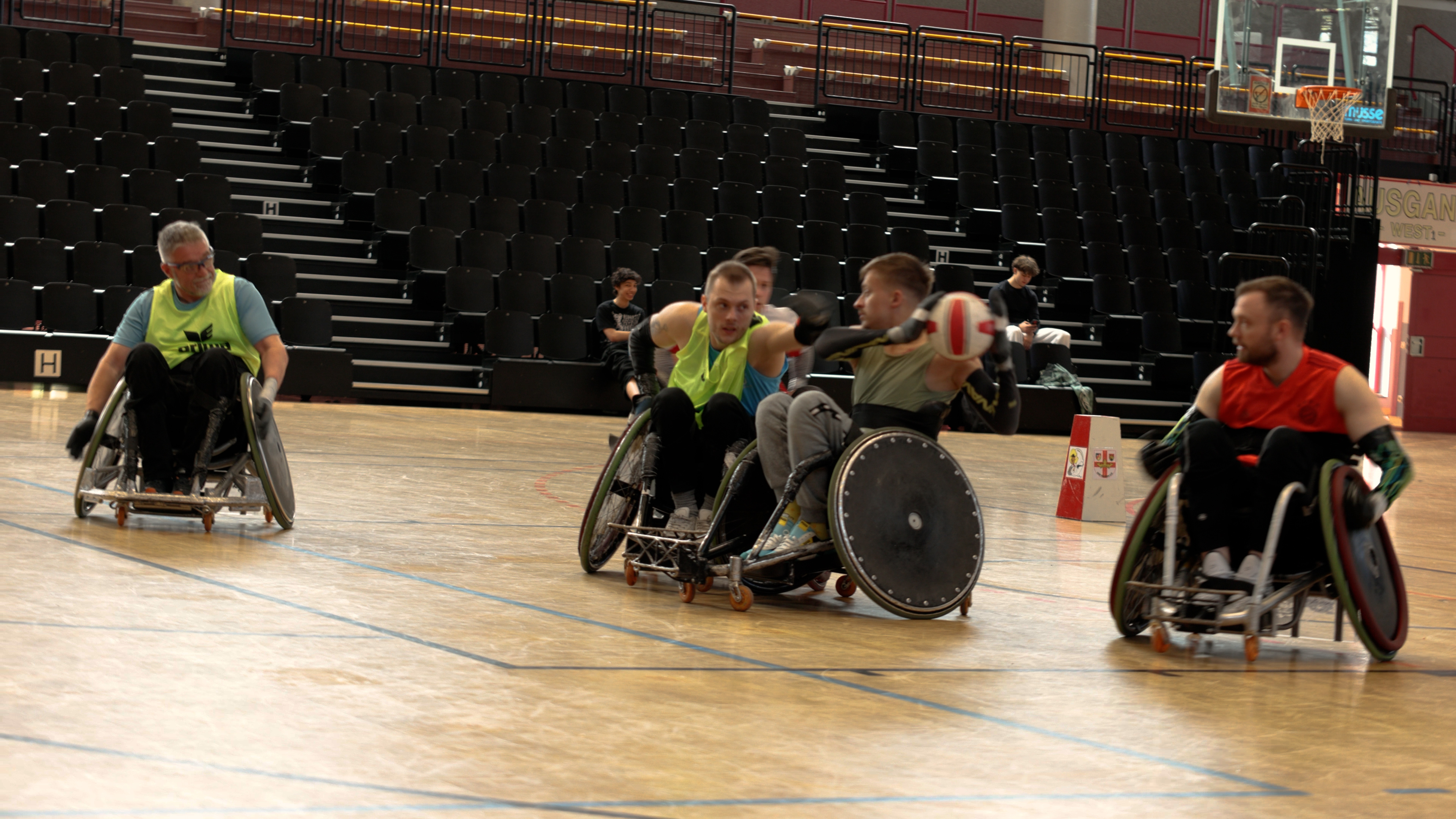 Florian spielt Rollstuhlrugby. erträgt dabei ein Neongelbes Leibchen und greift konzentriert nach dem Ball. 