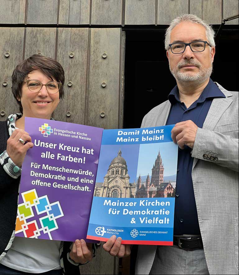 Pfarrerin Eva Lemaire und Dekan Andreas Klodt zeigen die Plakataktion.