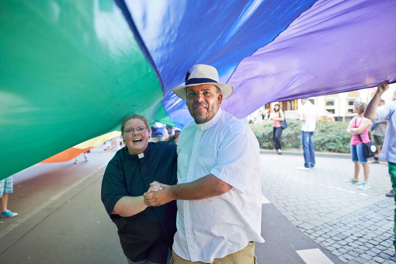 Pfarrer Nulf Schade-James (rechts) mit einem großen Regenbogentuch beim Christopher Street Day 2014