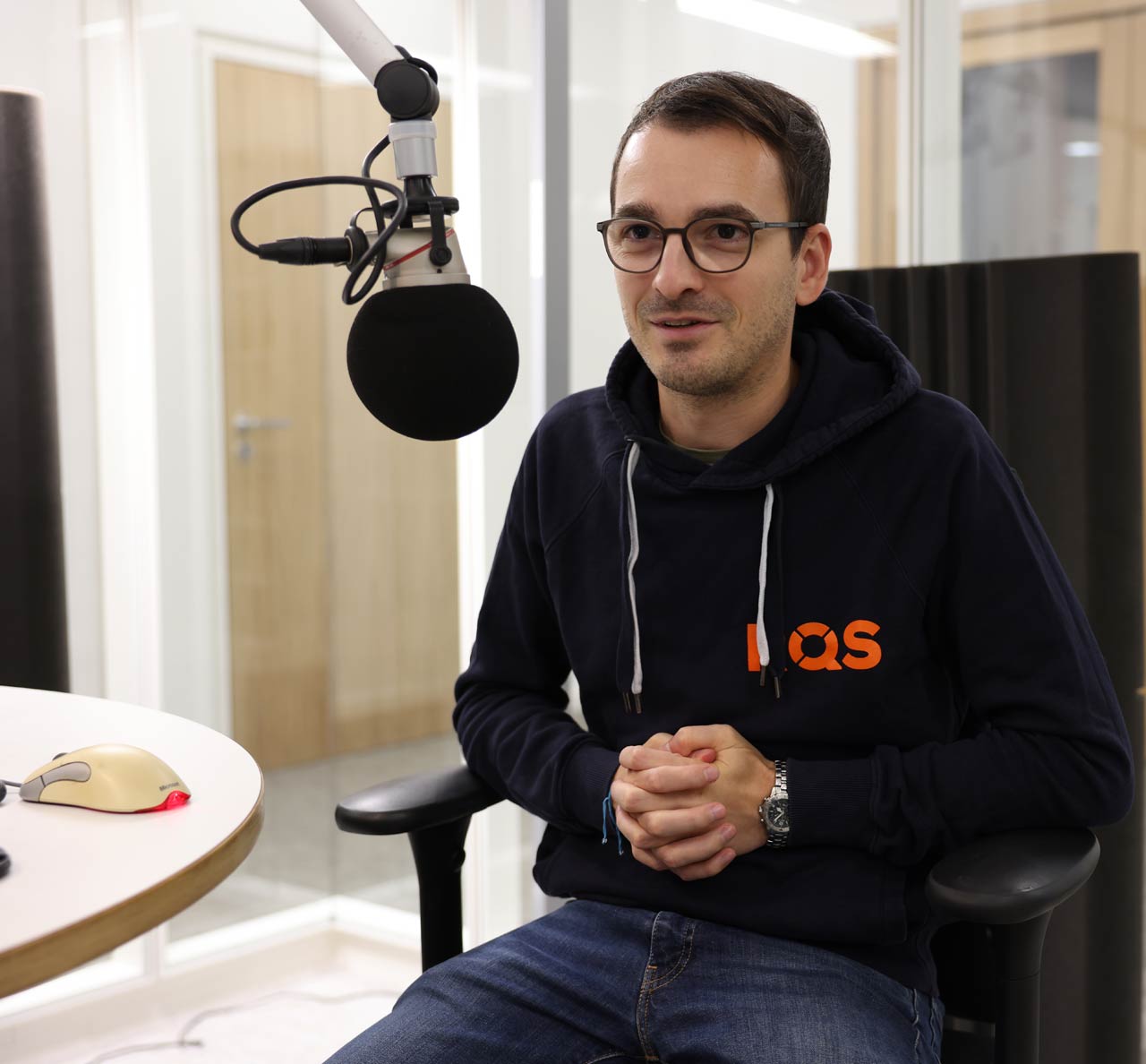 Stefen im Studio im Gep, im Vordergrund ist ein Mikro zu sehen. Er trägt einen Pulli mit Bändeln.