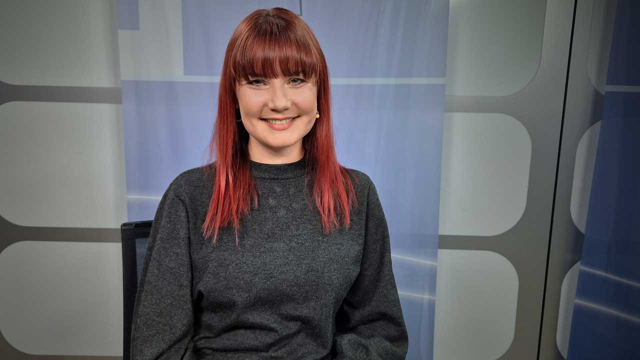 Sarah Straub sitzt im Alpha&Omega-Studio. Sie blickt freundlich in die Kamera. 