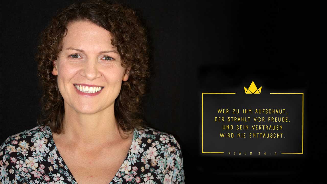 Portrait von Olga mit braunem lockigen Haar. Im Hintergrund der Bibelvers einer Hoffnungstasche: Wer zu ihm aufschaut, der strahlt vor Freude und sein Vertrauen wird nie enttäuscht. (Psalm 34:6)