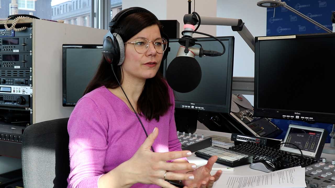 Journalistin Charlotte Mattes sitzt bei der Podcast-Aufnahme vorm Mikro.