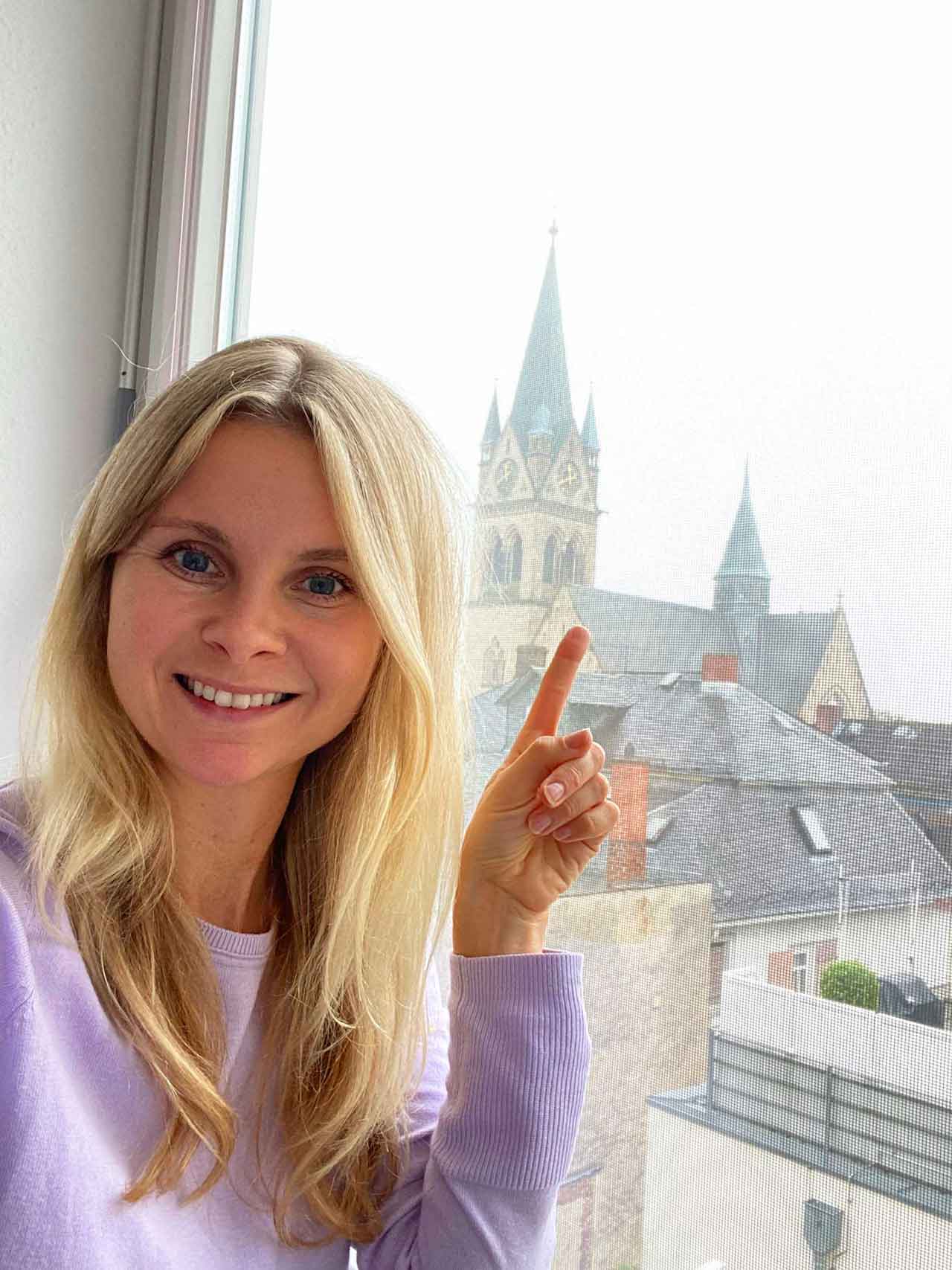 Redakteurin Carina im Home-Office mit Glockenturm im Hintergrund.