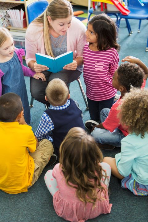 Eine Erzieherin liest Kindern aus einem Buch vor.