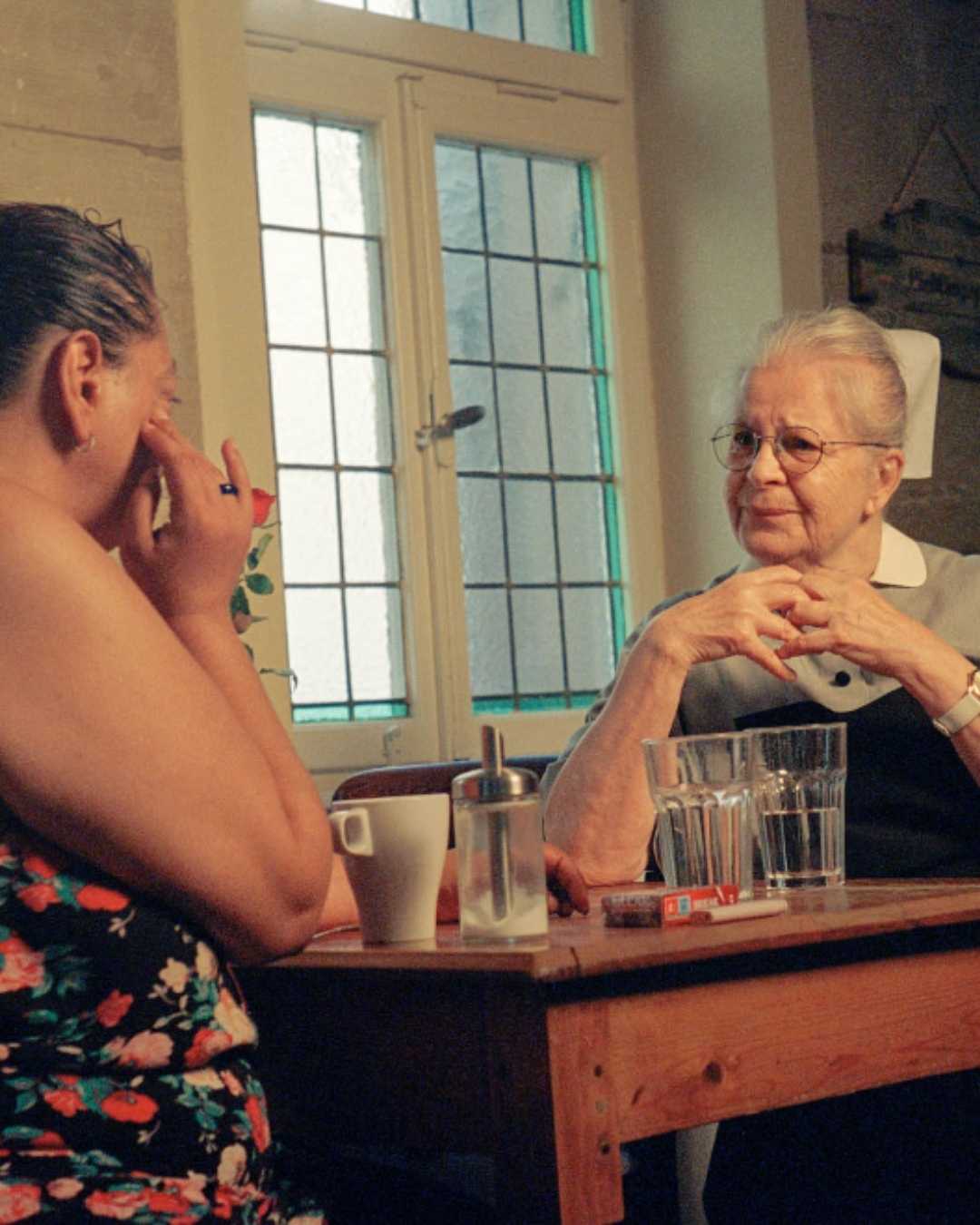 Zwei Frauen sitzen sich an einem Tisch gegenüber und unterhalten sich