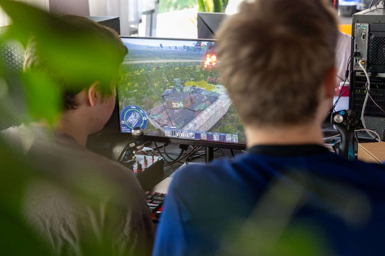 zwei Jugendliche spielen einen Panzersimulator
