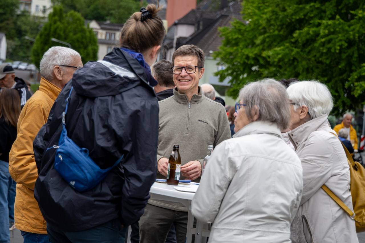 Eine Gruppe Menschen steht um einen Tisch und unterhält sich