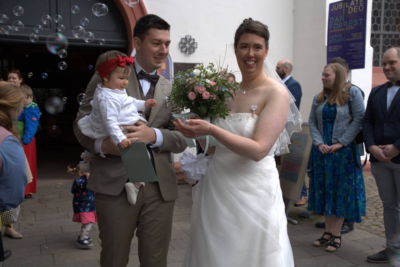 Hochzeitspaar mit Tochter vor Kirche