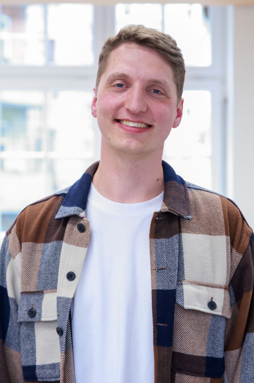 Gabriel steht vor einem Fenster und lacht