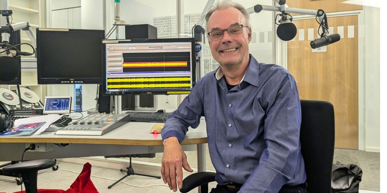 Andreas Goetze lacht in die Kamera, sitzend im Studio.