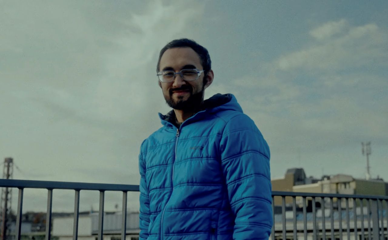 Salomo steht mit blauer Winterjacke an einer Brücke