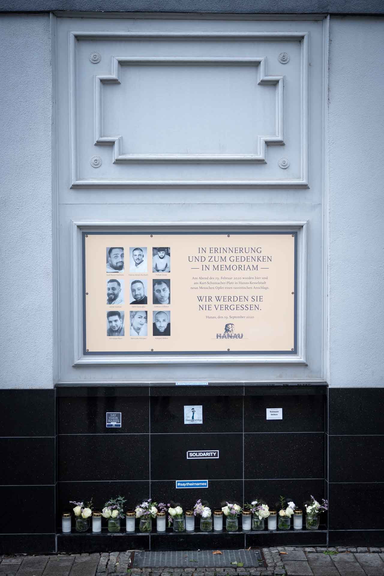 Gedenktafel am Tatort Heumarkt. Darauf Portraits der neun Ermordeten und der Text: „In Erinnerung und zum Gedenken - in Memoriam. Am Abend des 19. Februar 2020 wurden hier und am Kurt-Schumacher-Platz in Hanau-Kesselstadt neun Menschen Opfer eines rassistischen Anschlags. Wir werden sie nie vergessen. Hanau, den 19. September 2020“