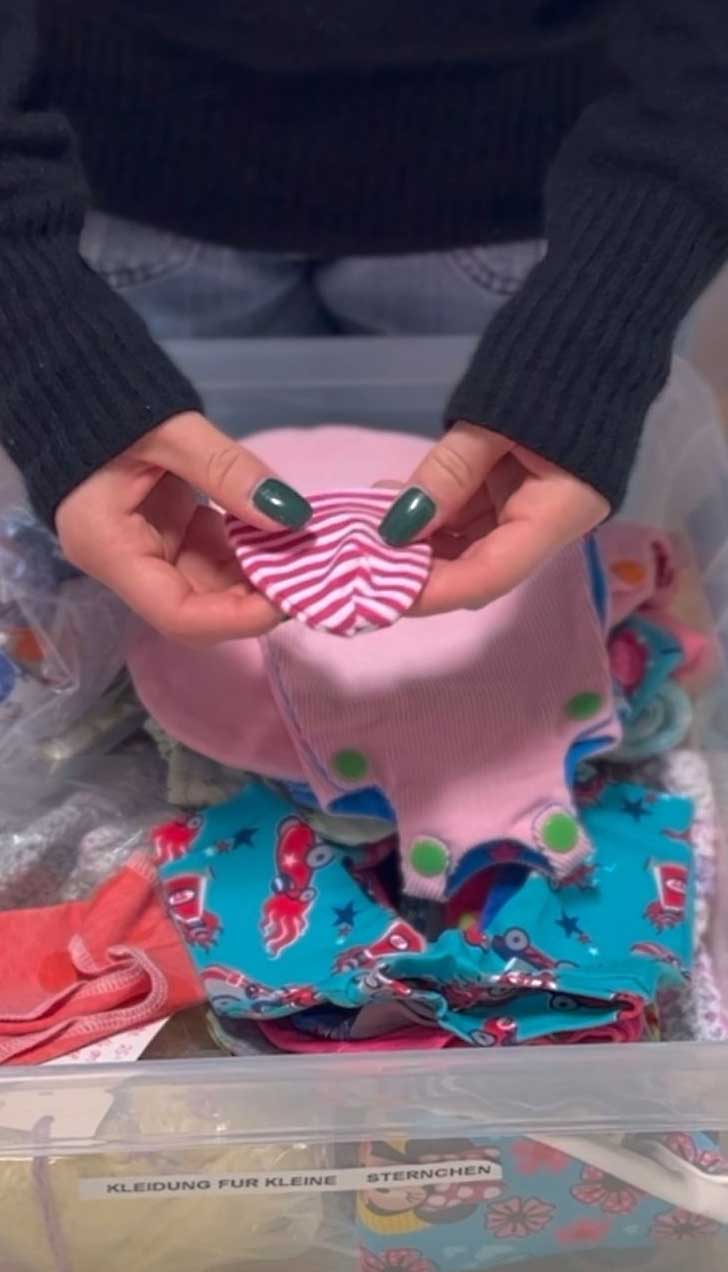 Eine Kiste mit Baby-Kleidung. Darauf das Schild „Kleidung für kleine Sternchen“