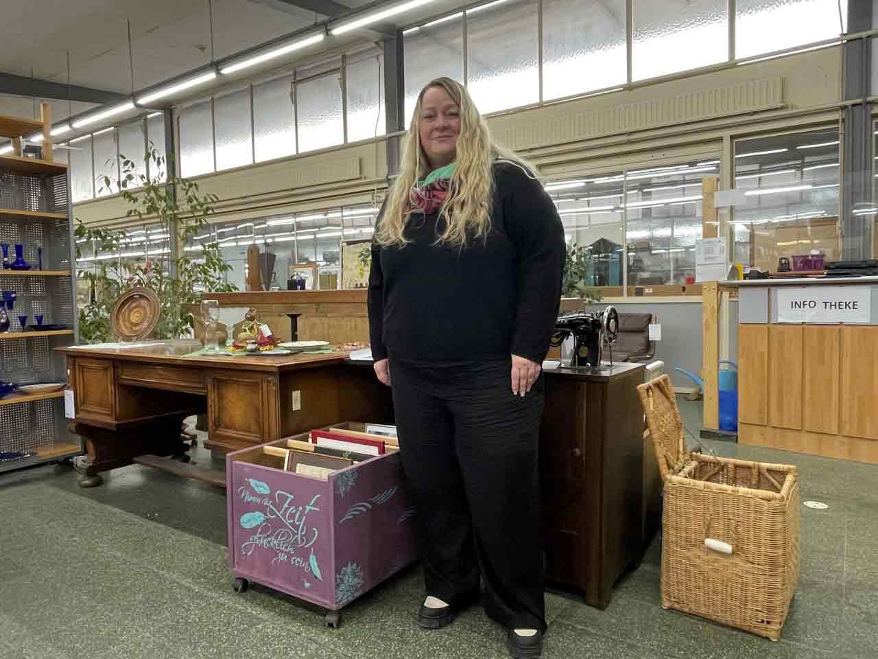 Frau steht in einer Halle mti gebrauchten Waren.