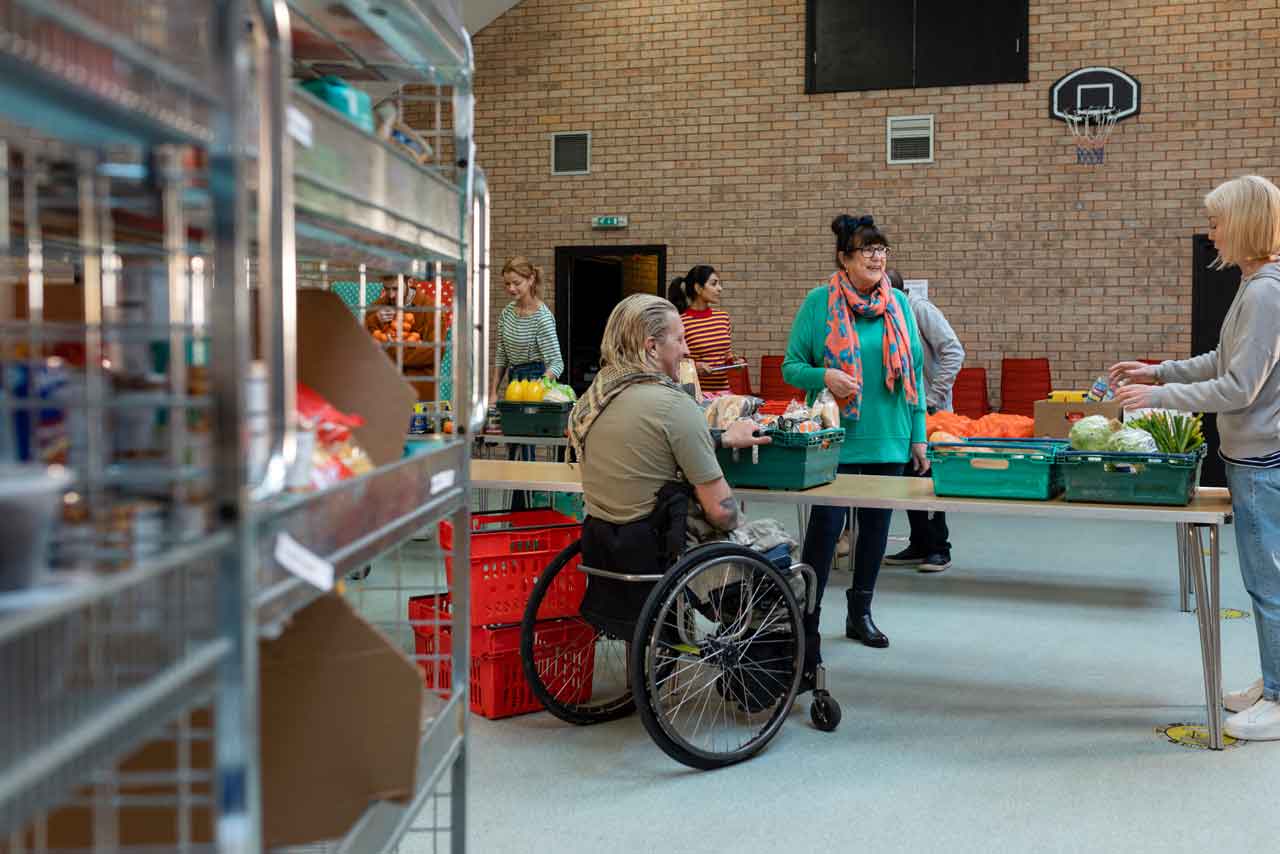 Gruppe von Freiwilligen, die Lebensmittelspenden auf Tische einer Lebensmittelbank im Nordosten Englands organisieren. Sie arbeiten zusammen.