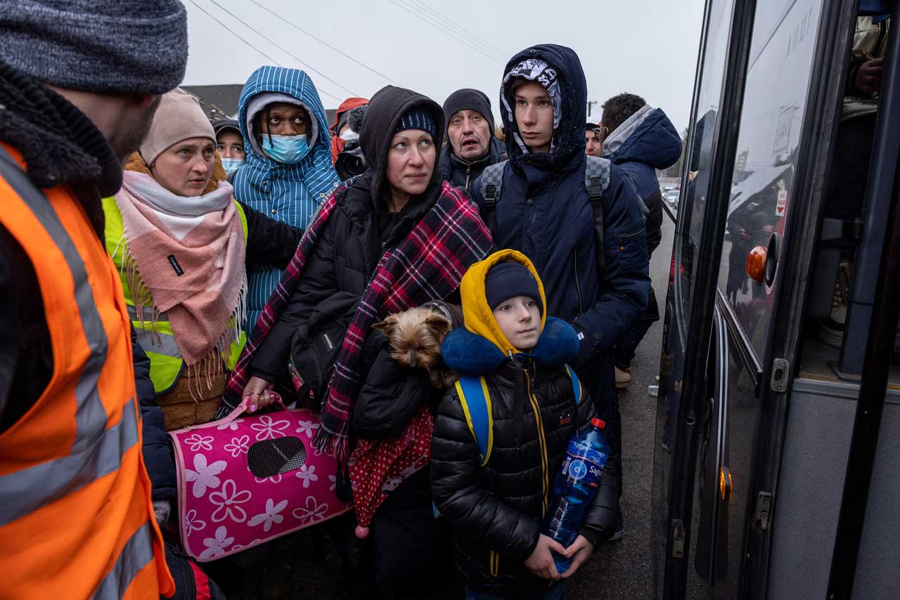 Menschen aus der Ukraine stehen vor einem Bus