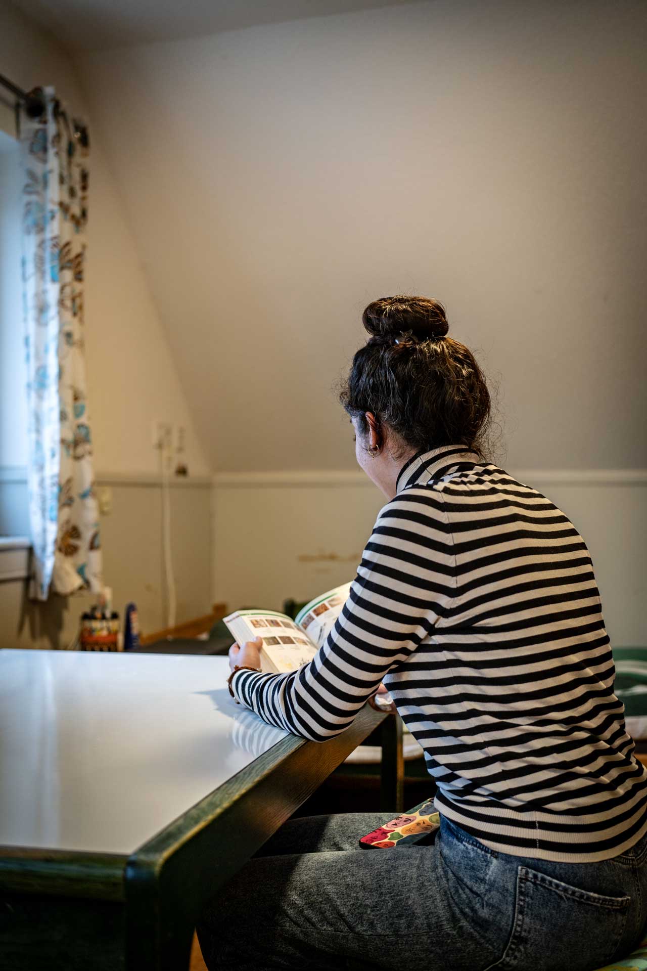 Geflüchtete aus dem Irak sitzt in der Wohnung für Geflüchtete am Tisch und liest in einem Deutsch-Lehrbuch