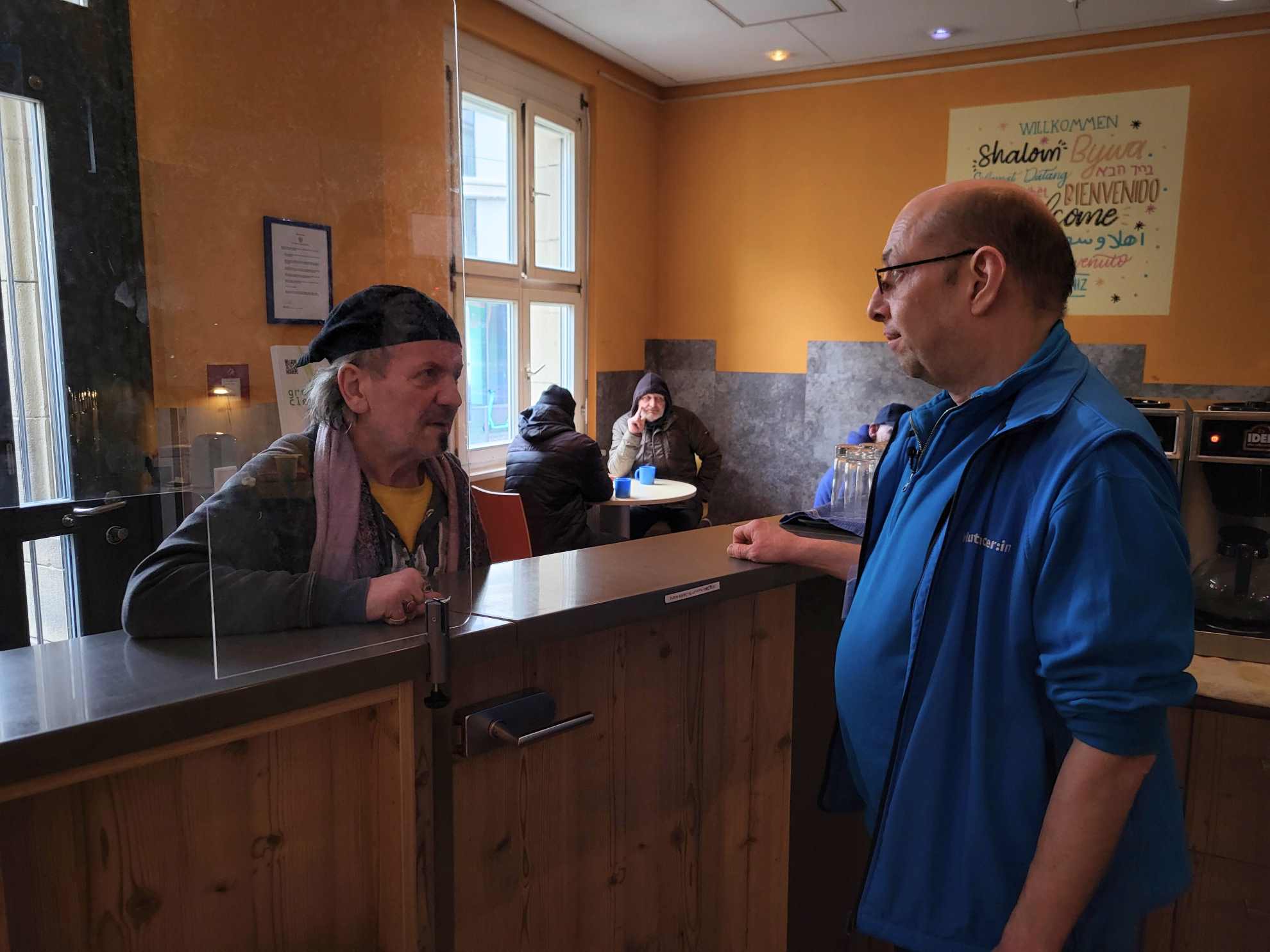 Bahnhofsmissions-Mitarbeiter Leif unterhält sich mit einem Gast der Bahnhofsmission Frankfurt