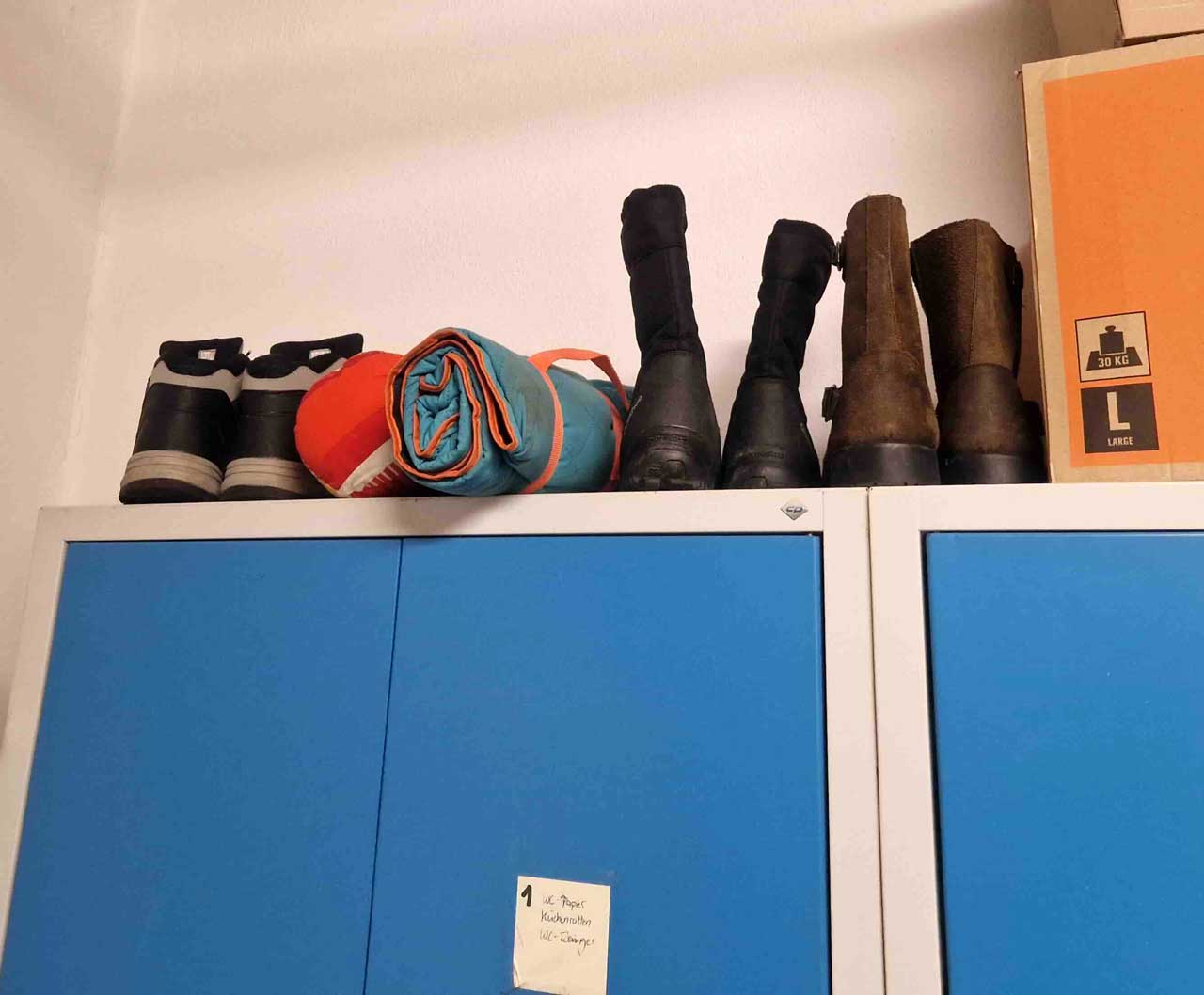 Schuhe und Schlafsack auf einem Spind