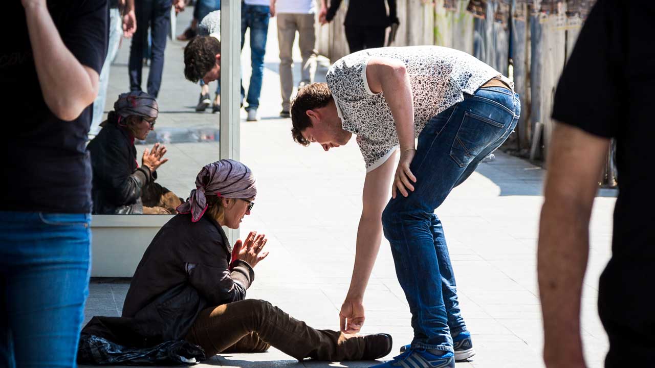  Mann gibt Geld an obdachlose Frau auf der Straße. 