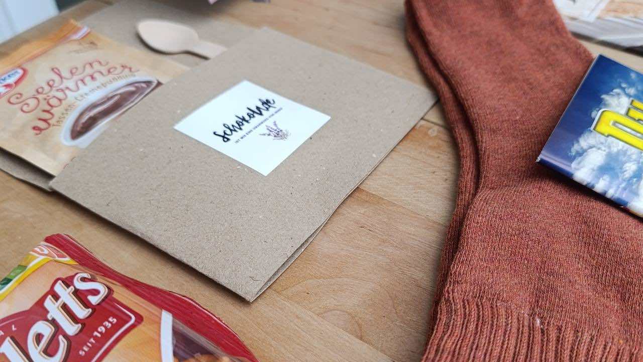 Rote Socken, Schokoladen und eine Packung Puddingpulver liegen auf einem TIsch.