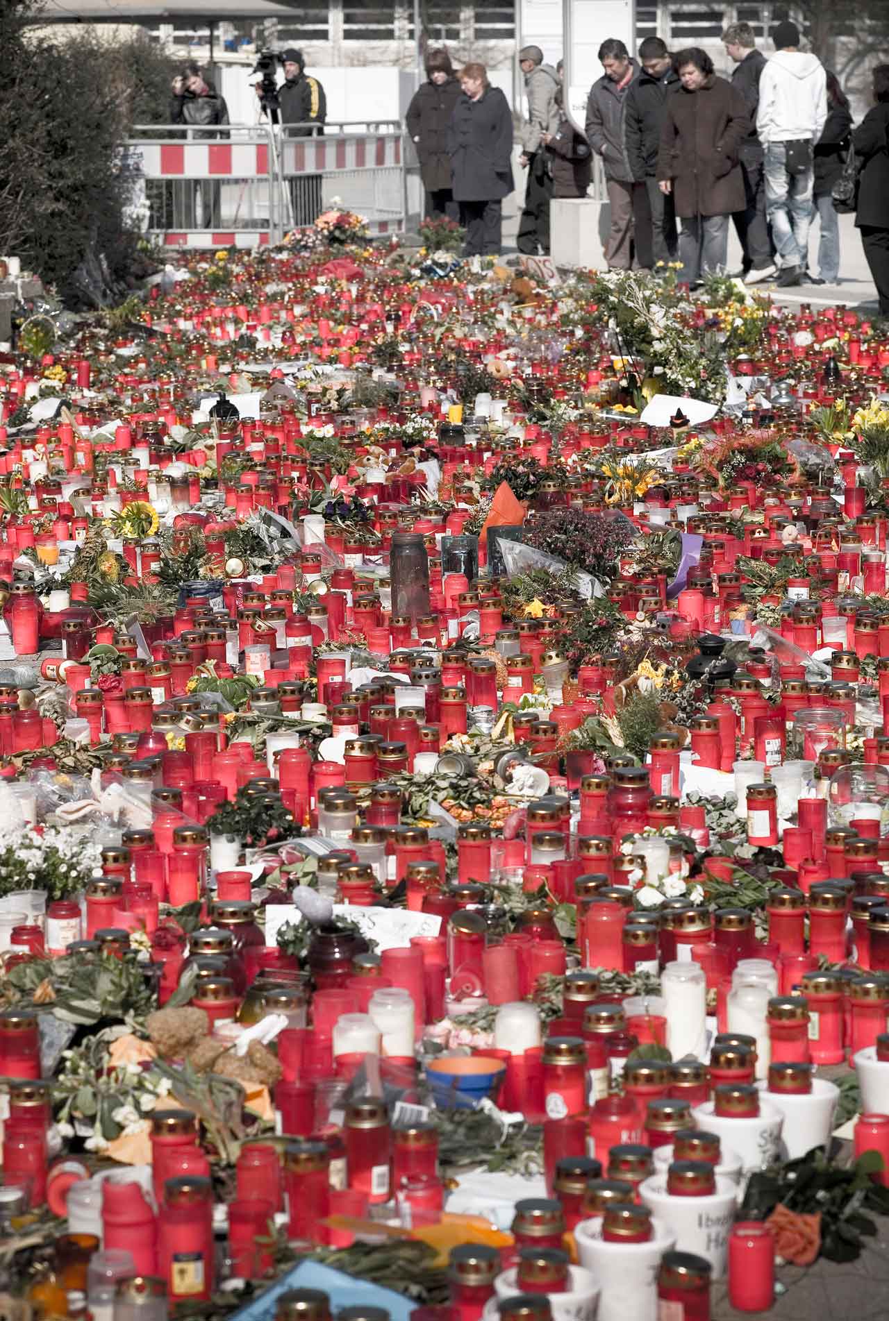 Trauernde vor der Albertville-Realschule betrachten die Blumen, Kränze und Kerzen