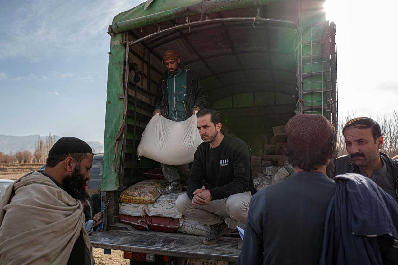 Serkan Eren und ein weiterer Helfer verteilt von der Laderampe eines Trucks Lebensmittel an umstehende Menschen.