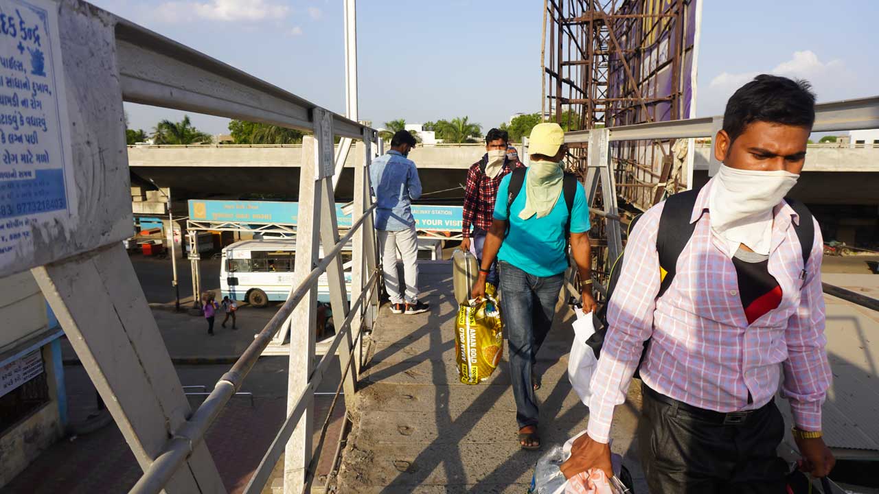 Indische Wanderarbeiter während des landesweiten COVID-19-Corona-Virus kehren mit Sonderzügen oder Bussen nach Hause zurück. Social Distancing und das Tragen von Masken am Bahnhof. Indische Polizei im Dienst.