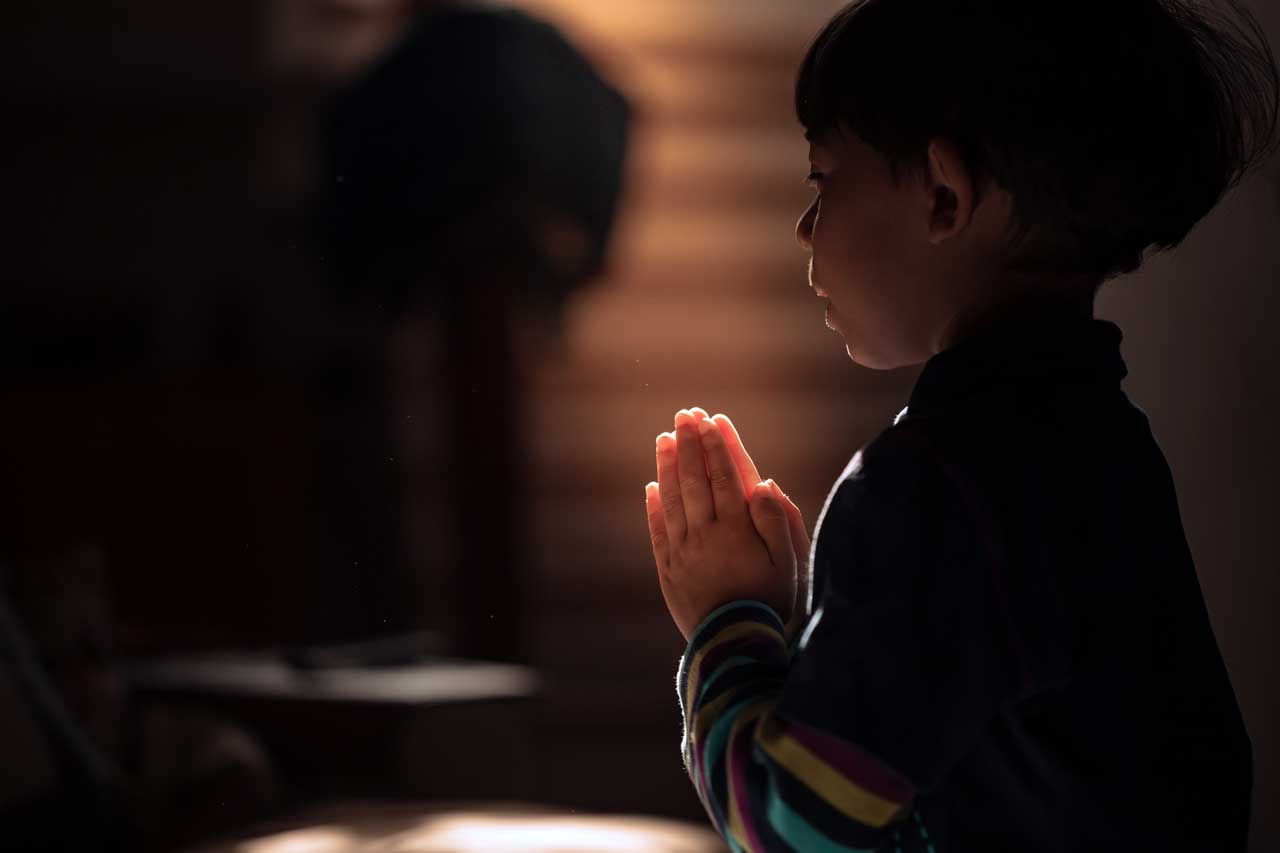 Kleiner Junge betend in der Kirche