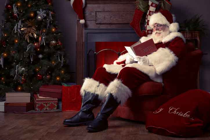 Weihnachtsmann sitzt im Sessel neben einem Tannenbaum
