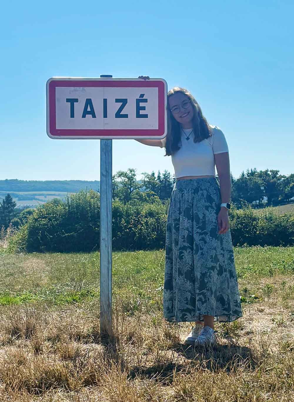 Pauline steht neben dem Ortsschild in Taizé