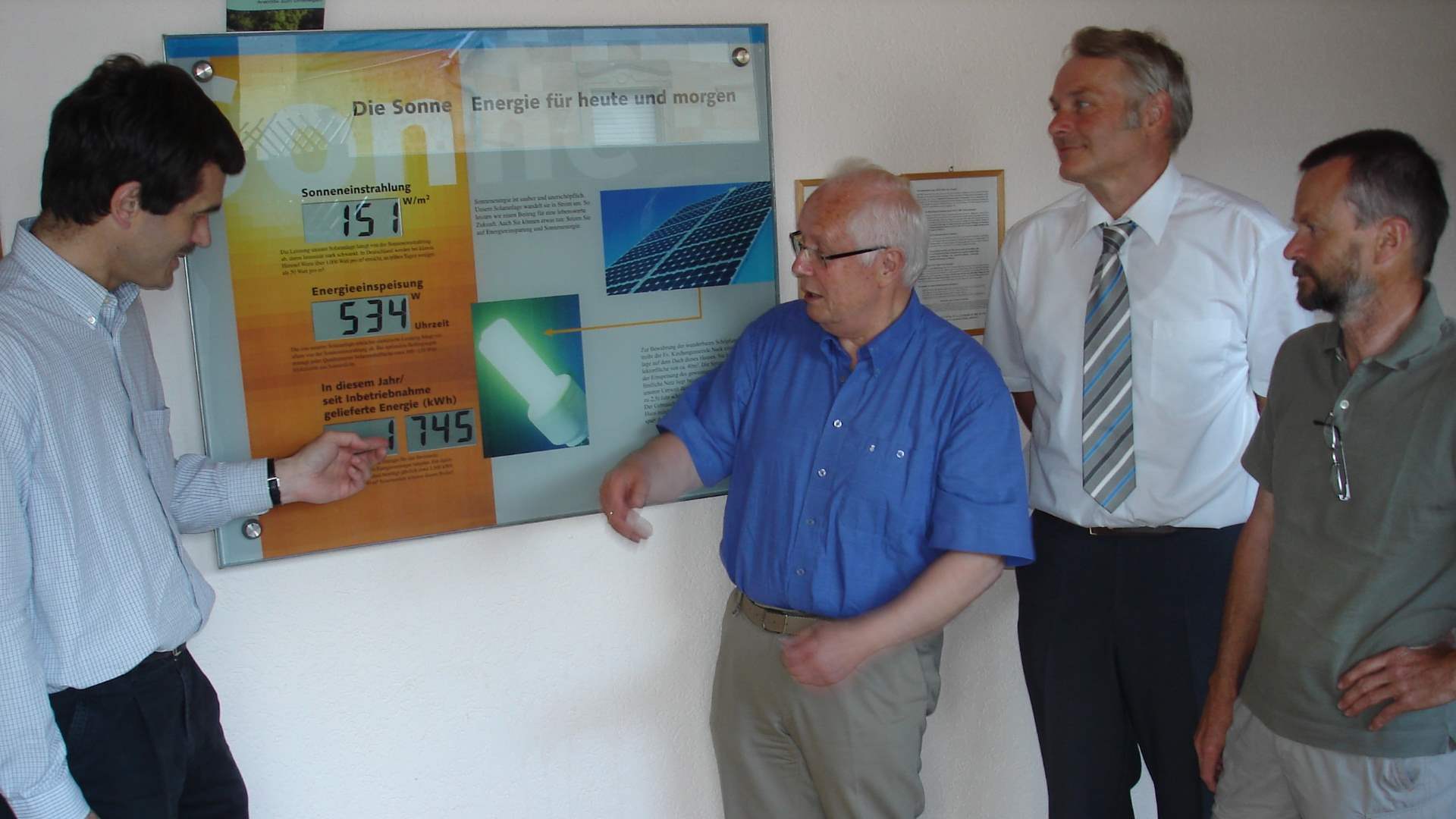 Vier Männer stehen um eine Messtafel einer Photovoltaik-Anlage