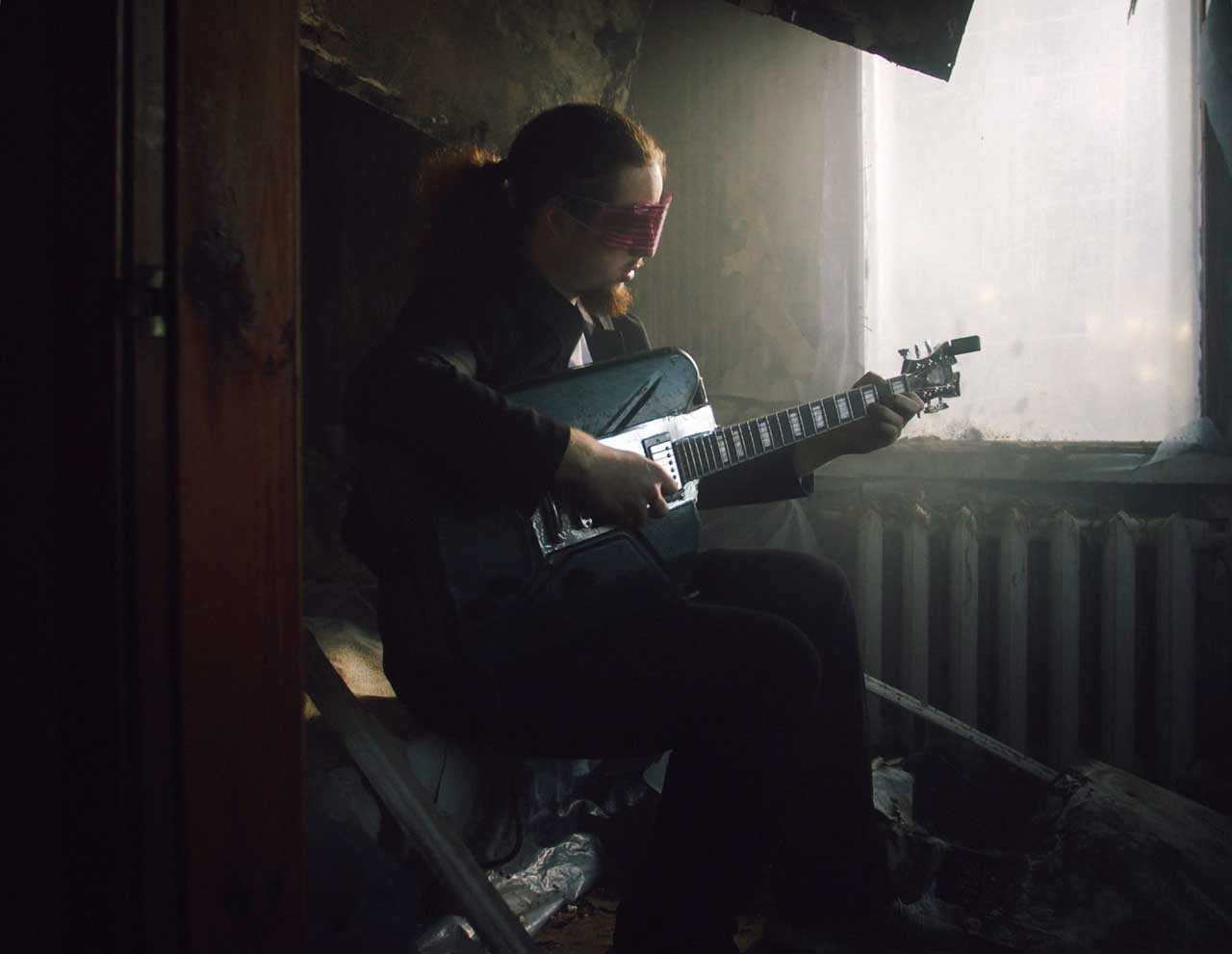Junger Mann spielt auf Gitarre aus Kriegsschrott