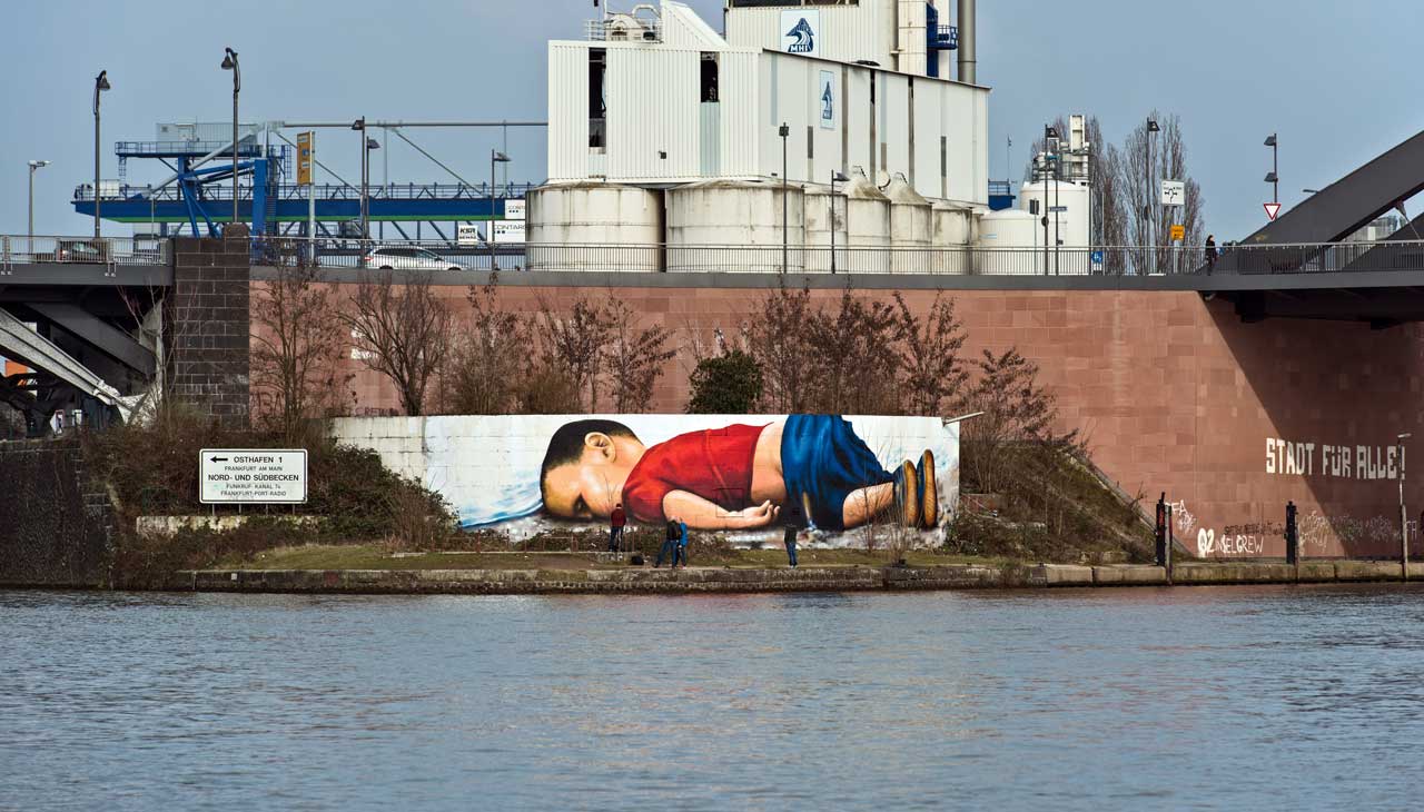 Im September 2015 wurde an der türkischen Küste ein kleiner syrischer Junge angespült - ertrunken auf der Flucht. Das Bild des toten Alan Kurdi prangt als Graffito auf einer Mauer am Frankfurter Osthafen, unweit der Europäischen Zentralbank. 