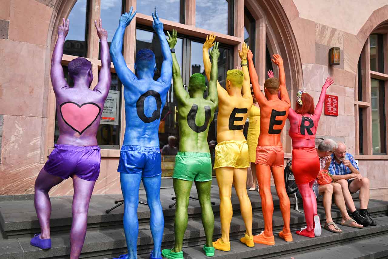 Beim Christopher Street Day in Frankfurt am Main am 15.07.2023 formen die Organisatoren der CSD-Parade auf dem Römerberg mit ihren bunt besprühten Körpern das Wort 'queer', um ein Statement für gleiche Rechte und gegen Ausgrenzung zu setzen. 