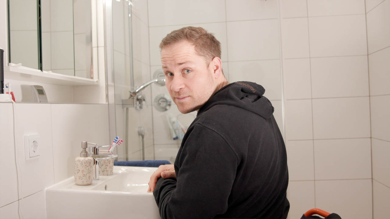 Lucas schaut in die Kamera, während er vor dem Waschbecken sitzt