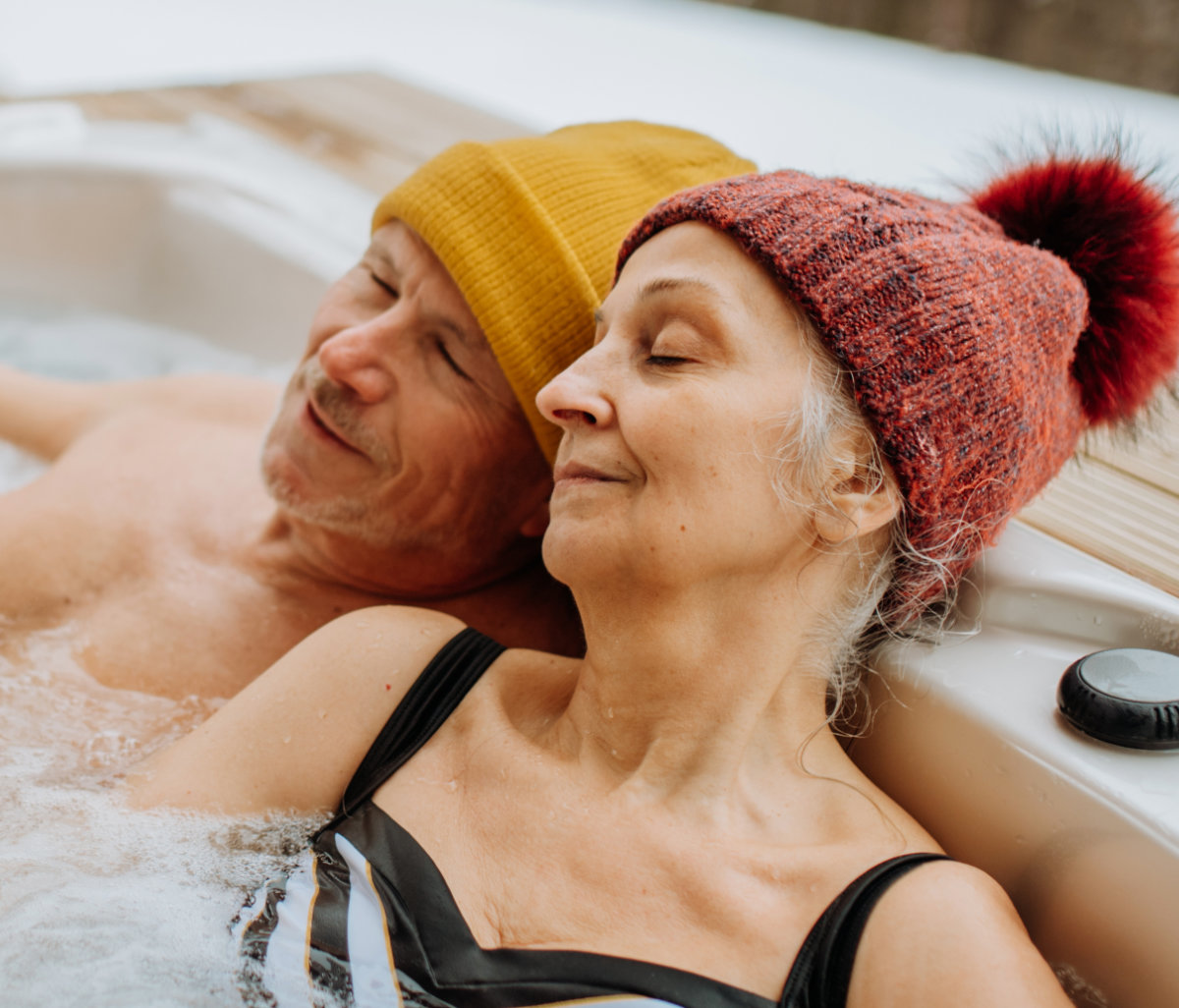 Mann und Frau mit einer roten und gelben Wollmütze sitzen im Whirlpool